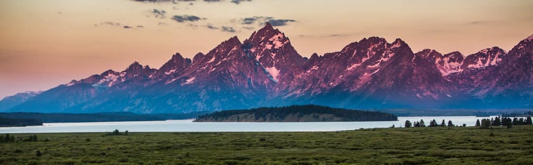 snow covered mountain near body of water during daytime