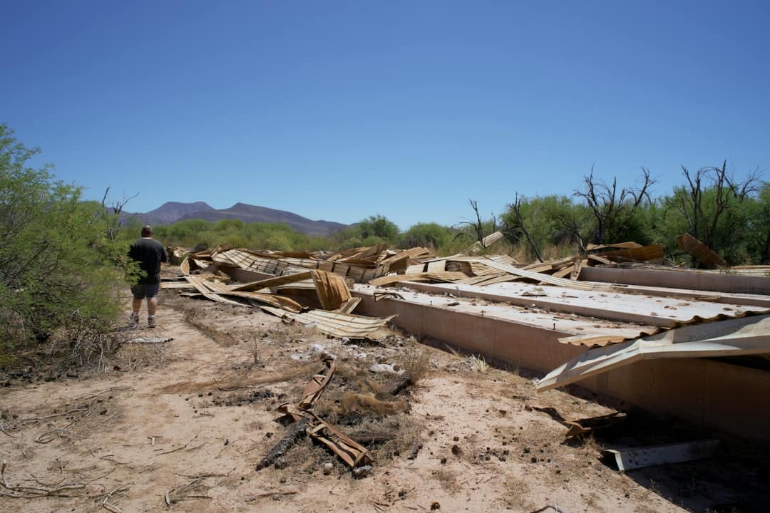 A man standing next to a bunch of boats on a dirt road