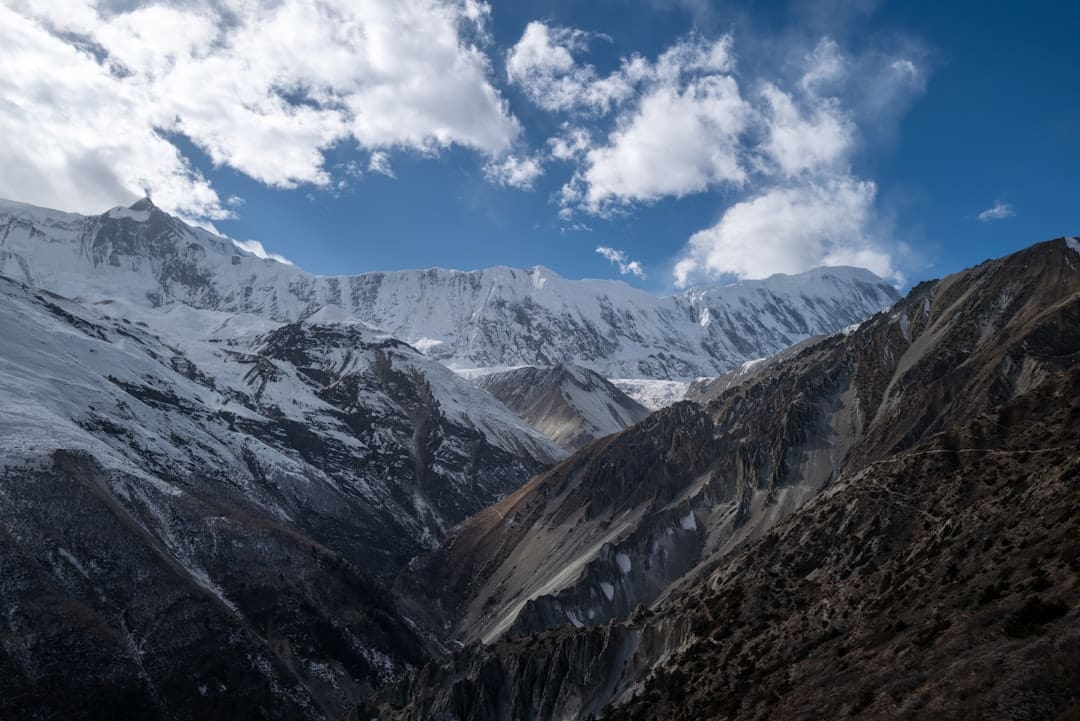 Snowy mountain range under a cloudy blue sky