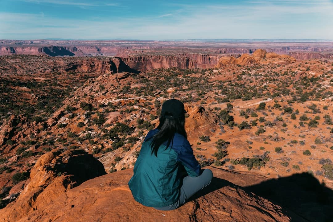 Woman sitting on cliff overlooking desert canyon